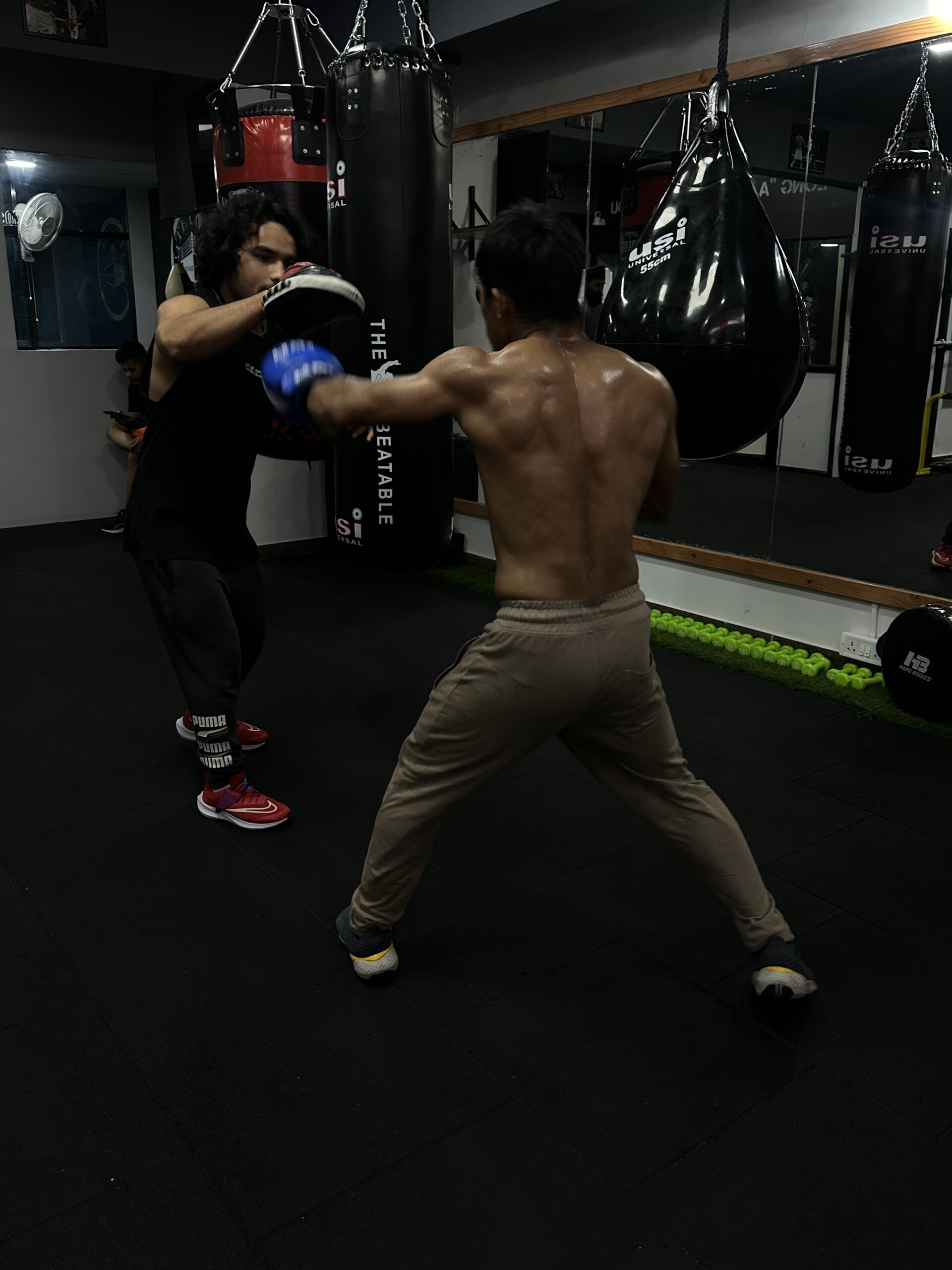 Boxing coach holding mitts while trainee practices punches at White Corner Boxing gym in Bangalore