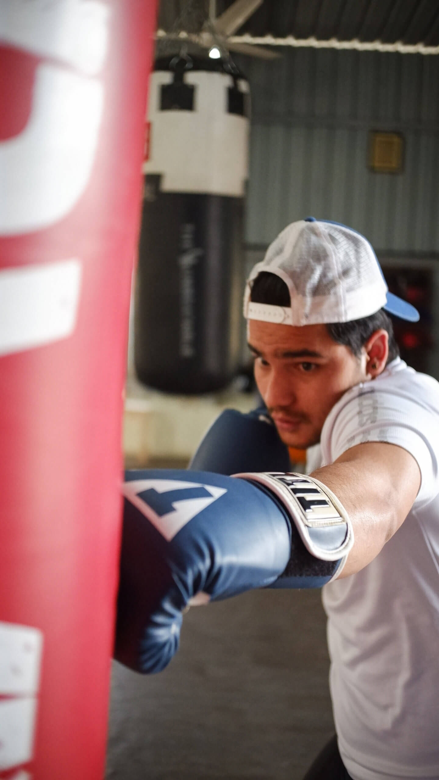 Focused boxer training with punching bag at White Corner Boxing Academy during boxing workout for fat loss in Bangalore
