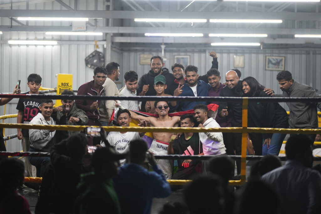 Professional boxer celebrating victory inside the ring at a White Corner Boxing Promotions event, surrounded by coaches, athletes, and supporters in Bangalore.